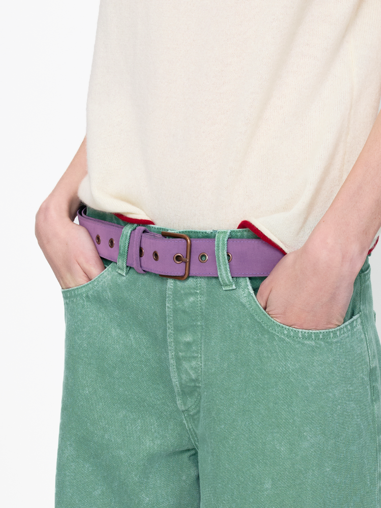 Person wearing green pants with a purple belt on a white background