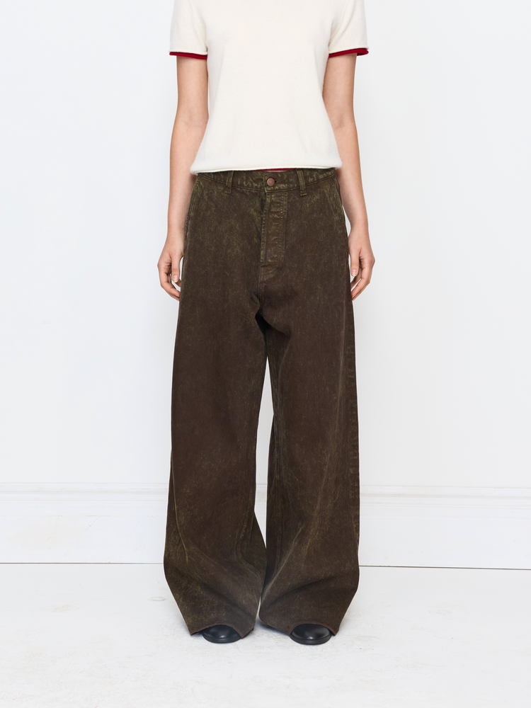 A model is shown from the chest down wearing dark brown wide-leg corduroy pants, a cream t-shirt with red trim, and black shoes against a white studio background.