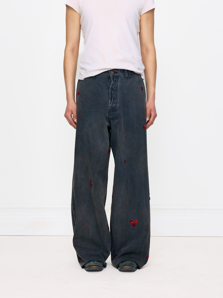 Person wearing dark jeans with red heart designs on a white background