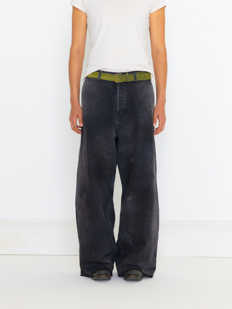 Person wearing black wide-leg pants with a green belt on a white background