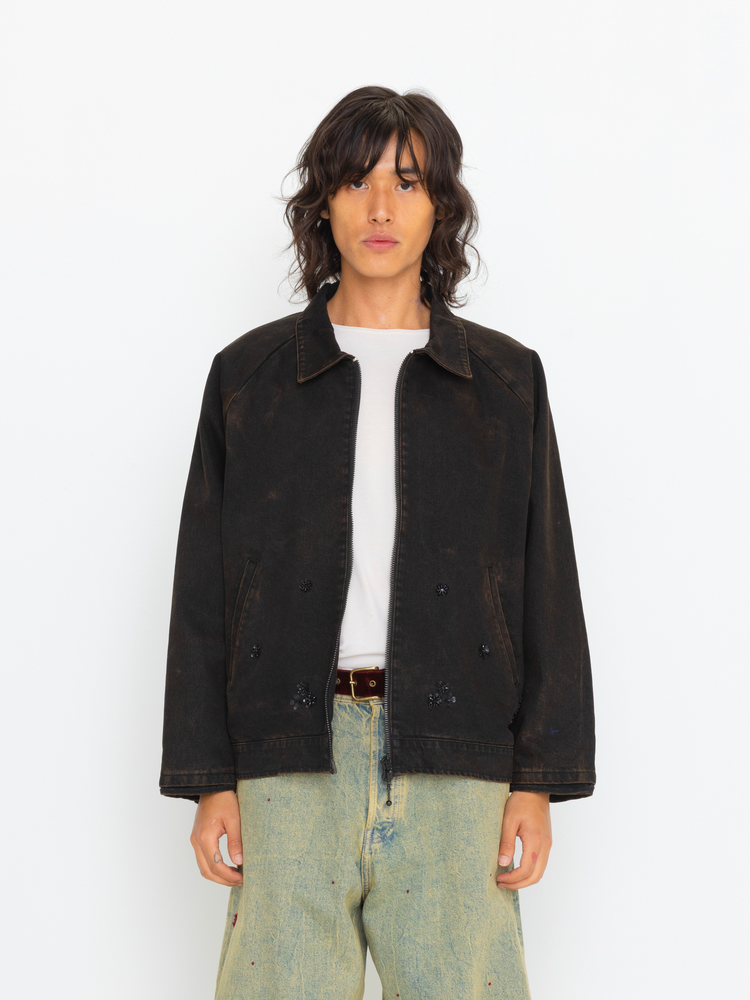 Person wearing a black jacket and light blue jeans on a white background