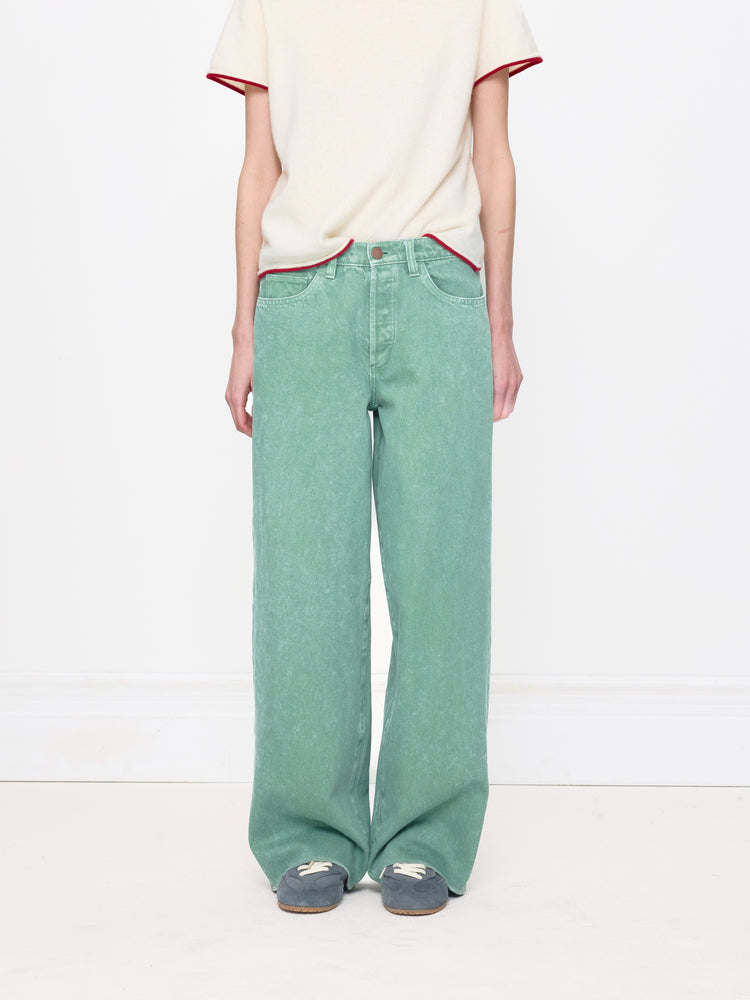 Person wearing a white top with red trim and green pants on a white background