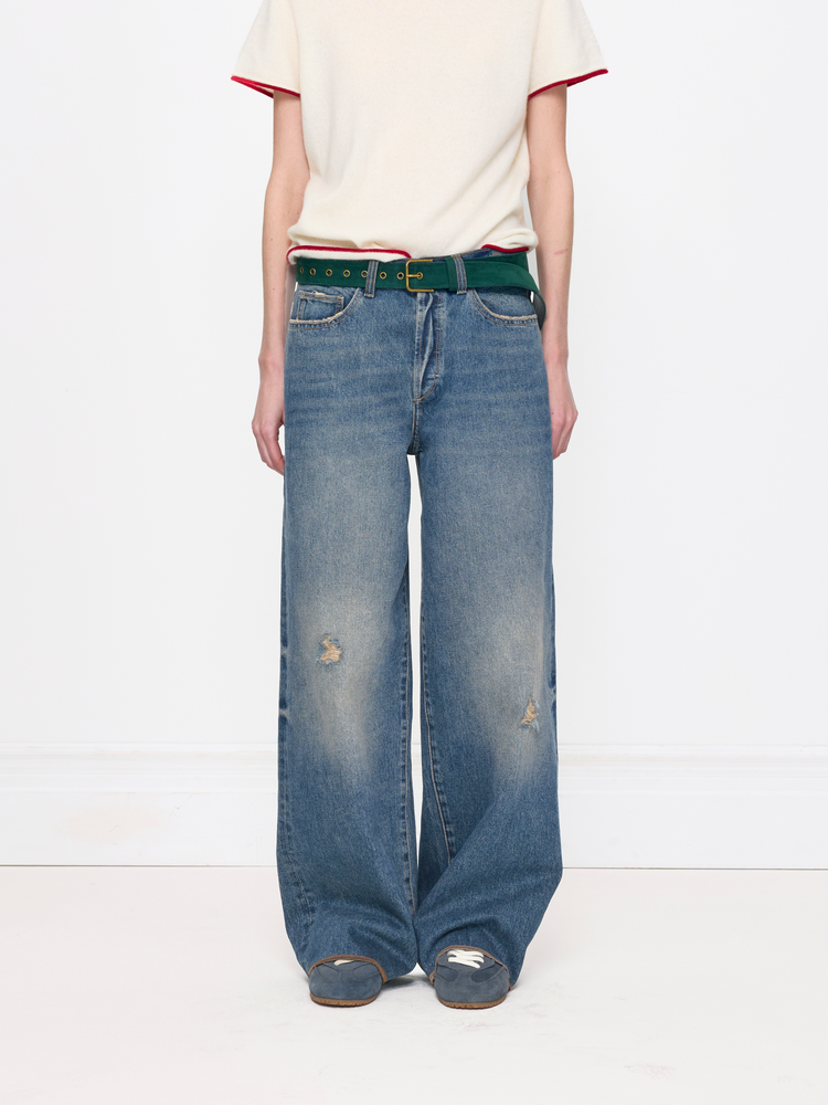 Person wearing blue jeans and a white shirt with red trim on a white background