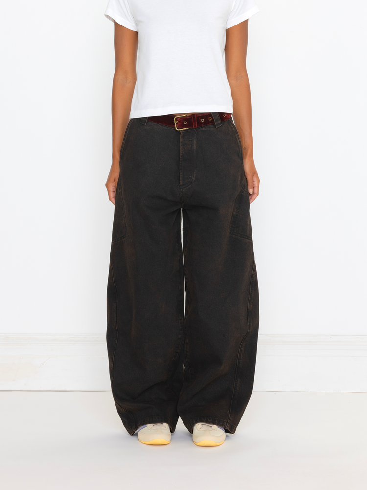 Person wearing black wide-leg pants with a white shirt and white shoes on a light background