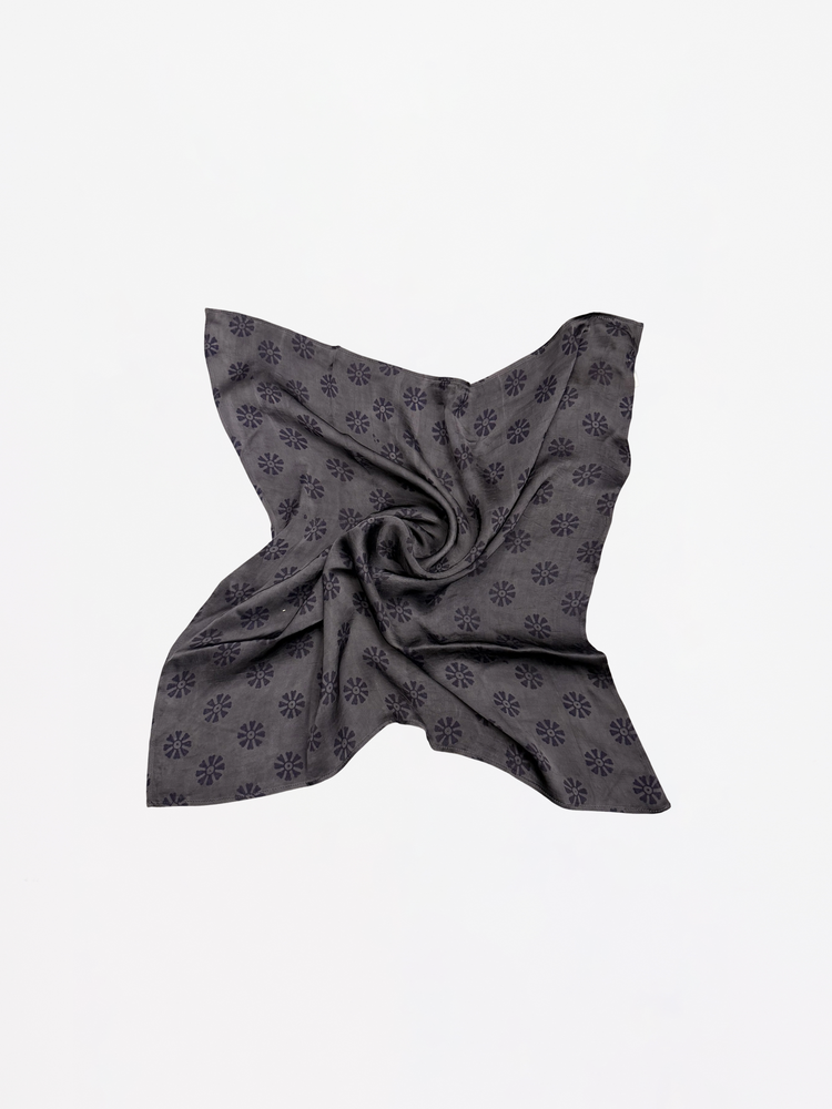 Dark gray patterned fabric folded into a triangle on a light gray background